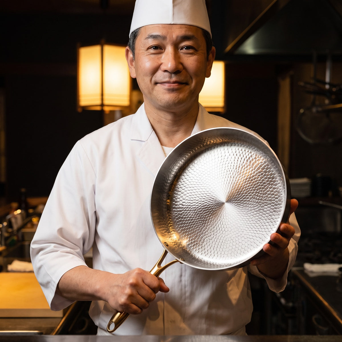 Hatori Kōmyō 光明 Kin 金 Edition – Hammered High-Wall Titanium Pan, held by a chef